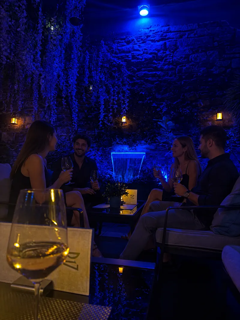 Gäste in der blau beleuchteten Lounge an der Wasserfallwand